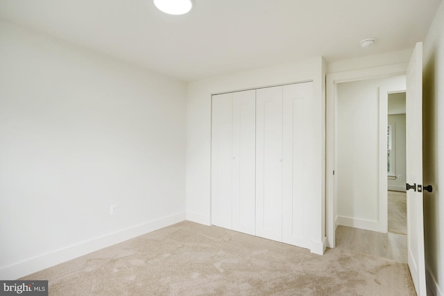 unfurnished bedroom featuring light carpet and a closet