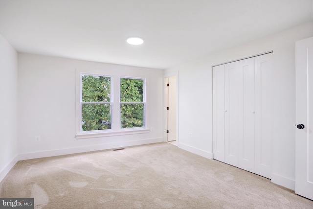 unfurnished bedroom featuring light carpet and a closet