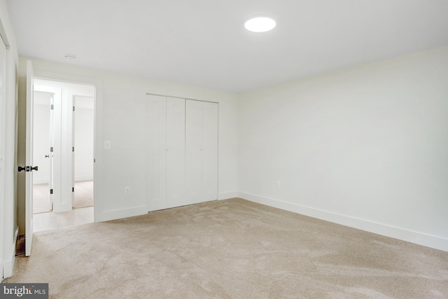 unfurnished bedroom with a closet and light colored carpet