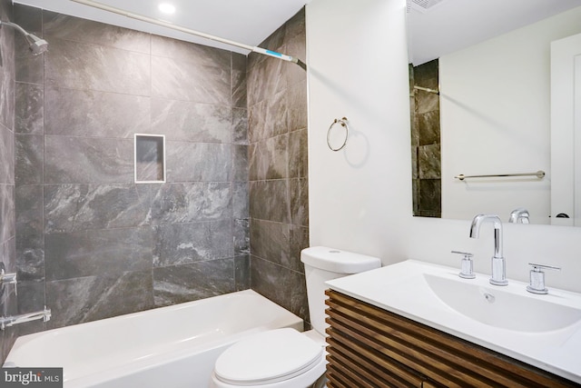 full bathroom featuring tiled shower / bath, vanity, and toilet