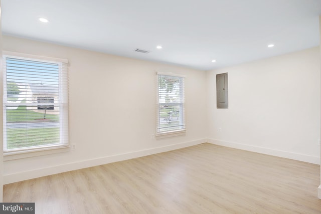 spare room featuring plenty of natural light, light wood-type flooring, and electric panel