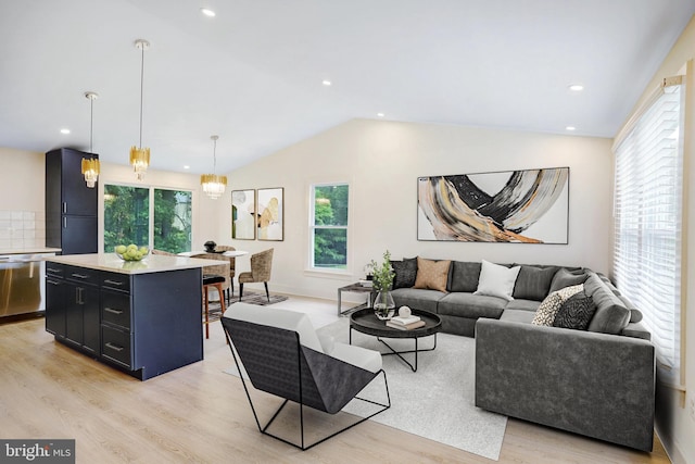 living room featuring an inviting chandelier, light hardwood / wood-style floors, and vaulted ceiling