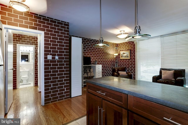 kitchen featuring tile walls, light hardwood / wood-style floors, and decorative light fixtures