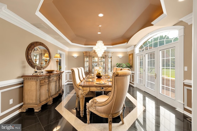 dining space with a raised ceiling, a notable chandelier, and ornamental molding