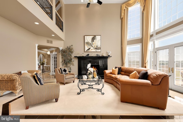 living room featuring ceiling fan, a towering ceiling, and french doors