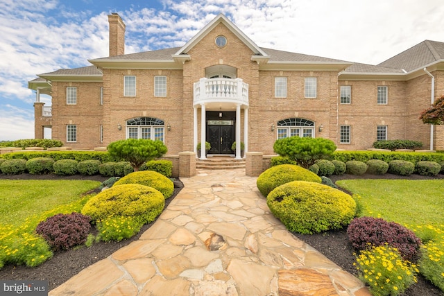 view of front facade featuring a balcony and a front lawn