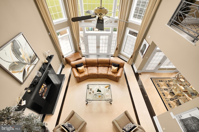 living room featuring ceiling fan, a towering ceiling, and french doors