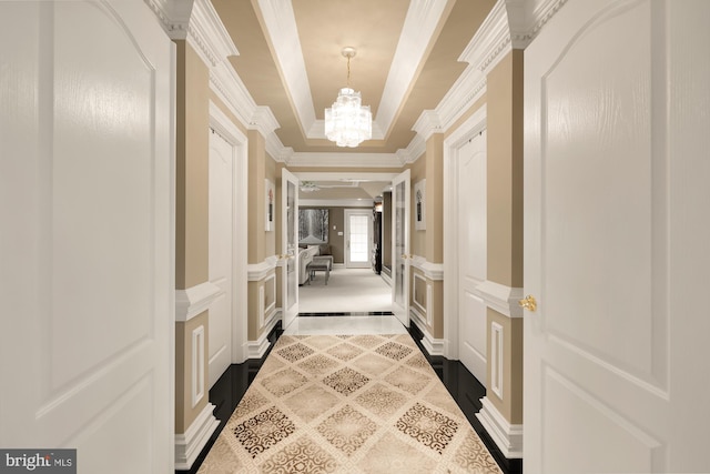 corridor featuring crown molding and a chandelier