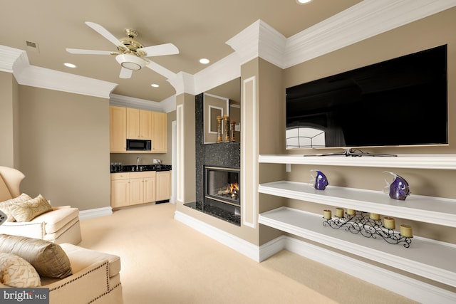 living room featuring a premium fireplace, ceiling fan, light colored carpet, and ornamental molding