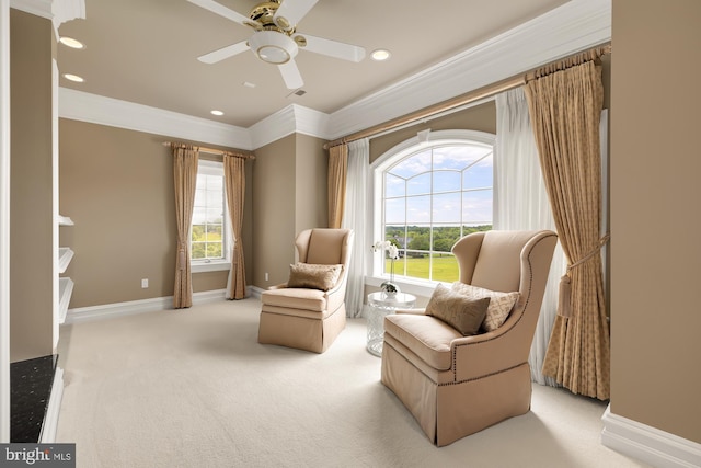 sitting room with light carpet, ornamental molding, ceiling fan, and a healthy amount of sunlight