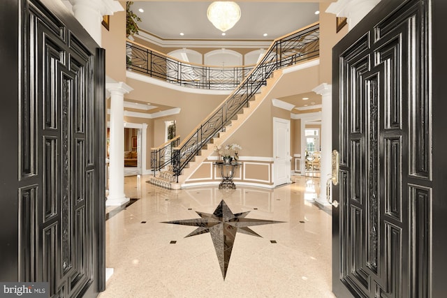 foyer with a high ceiling, decorative columns, and crown molding