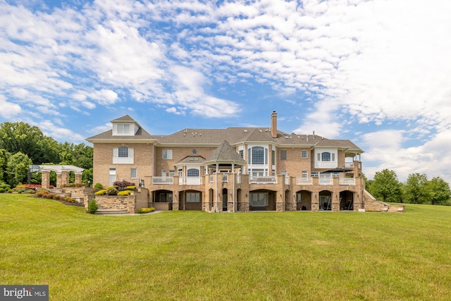 back of house with a lawn and a balcony