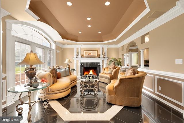 interior space featuring a raised ceiling, a fireplace, and decorative columns