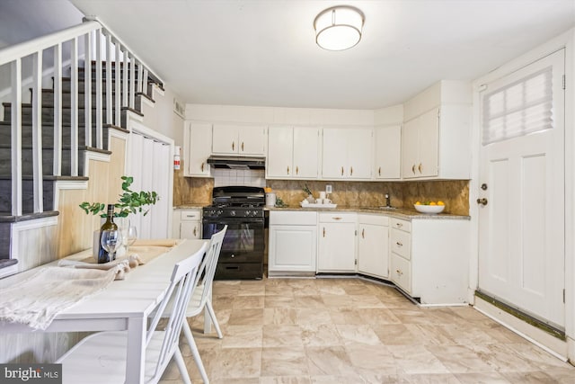 kitchen with white cabinets, gas stove, and tasteful backsplash