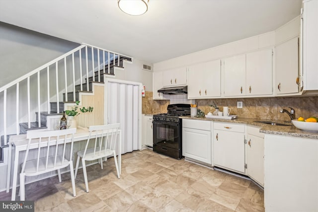 kitchen with decorative backsplash, light stone countertops, sink, black gas range, and white cabinetry