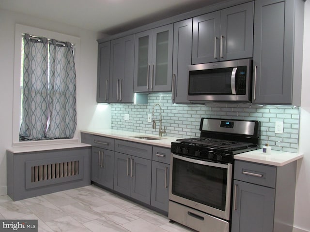 kitchen featuring appliances with stainless steel finishes, tasteful backsplash, sink, gray cabinetry, and light tile patterned flooring