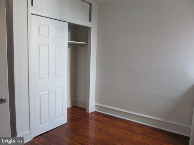 unfurnished bedroom featuring a closet and dark hardwood / wood-style flooring