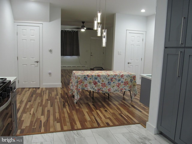 dining area with light wood-type flooring, a baseboard radiator, and ceiling fan