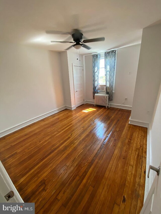 spare room with ceiling fan, dark hardwood / wood-style flooring, and radiator heating unit