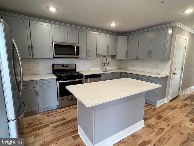 kitchen featuring gray cabinetry, sink, a kitchen island, and stainless steel appliances