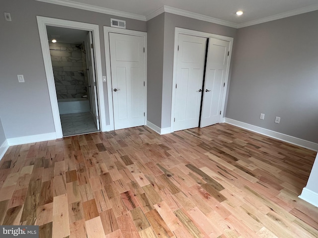 unfurnished bedroom featuring ensuite bath, a closet, light hardwood / wood-style flooring, and ornamental molding