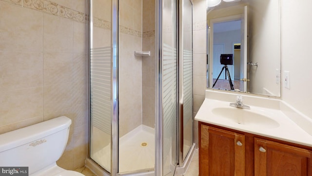 bathroom with walk in shower, vanity, toilet, and tile walls