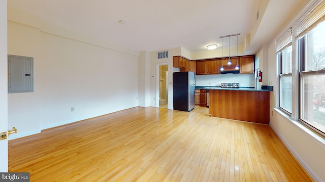 kitchen featuring ventilation hood, decorative light fixtures, light hardwood / wood-style flooring, electric panel, and stainless steel refrigerator