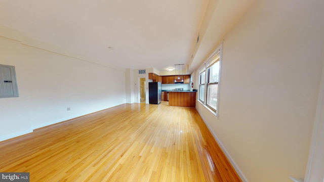 unfurnished living room featuring electric panel and light hardwood / wood-style flooring