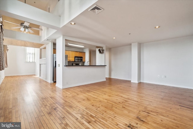 unfurnished living room with ceiling fan, sink, and light wood-type flooring