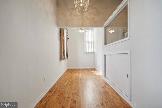 interior space with ceiling fan with notable chandelier and light wood-type flooring