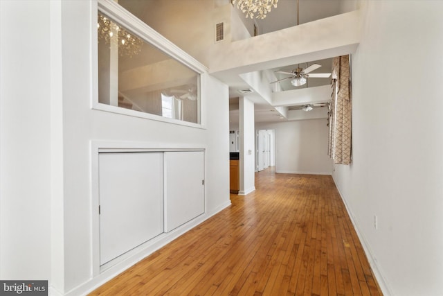 hall featuring hardwood / wood-style floors, a high ceiling, and an inviting chandelier