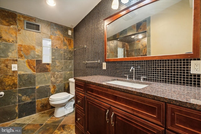 bathroom featuring tasteful backsplash, vanity, tile walls, and toilet