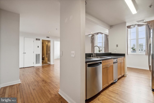 kitchen with light brown cabinetry, sink, stainless steel appliances, and light hardwood / wood-style floors