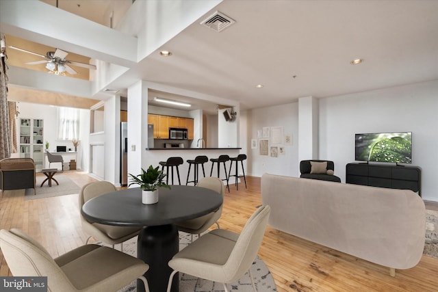 dining area featuring ceiling fan, sink, and light hardwood / wood-style flooring