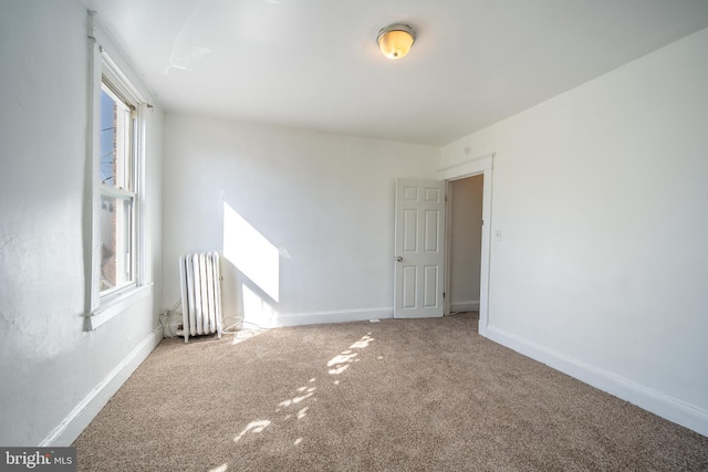 carpeted empty room with baseboards, a healthy amount of sunlight, and radiator heating unit