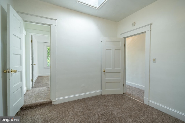 carpeted spare room with baseboards and a skylight