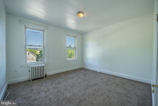 empty room with radiator heating unit, carpet, and baseboards