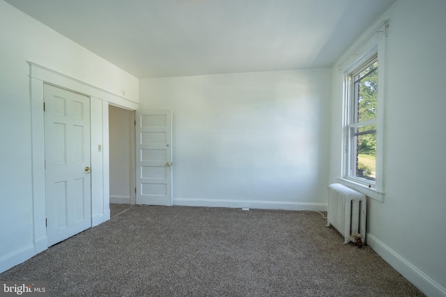 carpeted empty room featuring radiator heating unit and baseboards