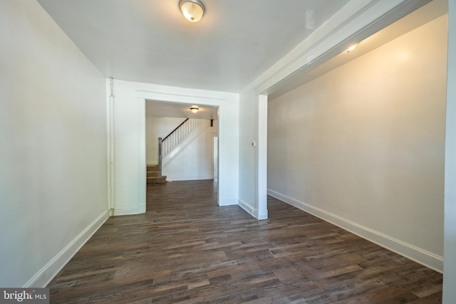 spare room with baseboards, stairs, and dark wood-type flooring