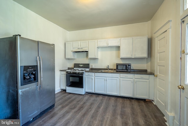 kitchen featuring a sink, stainless steel appliances, dark countertops, and dark wood-style flooring