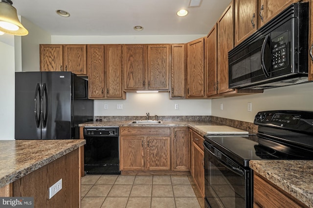 kitchen featuring dark stone countertops, sink, light tile patterned floors, and black appliances