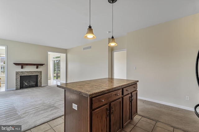 kitchen with a tile fireplace, a center island, pendant lighting, light carpet, and dark brown cabinets