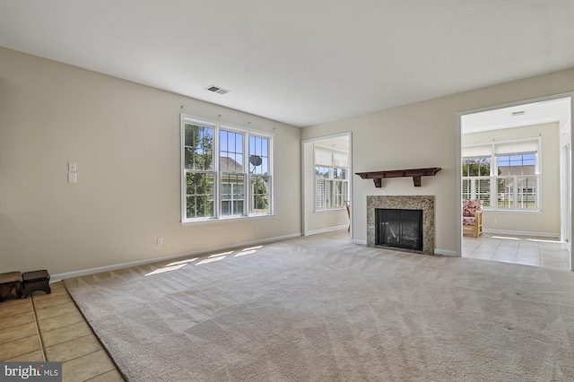 unfurnished living room with a tile fireplace and light carpet