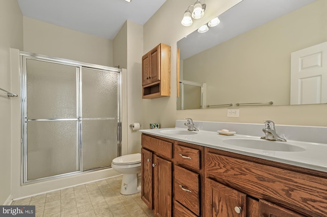 bathroom with vanity, toilet, and a shower with door