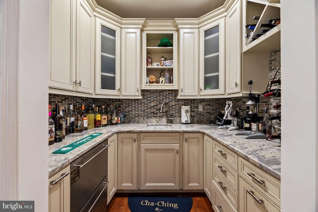 kitchen featuring backsplash, light stone countertops, sink, and cream cabinets