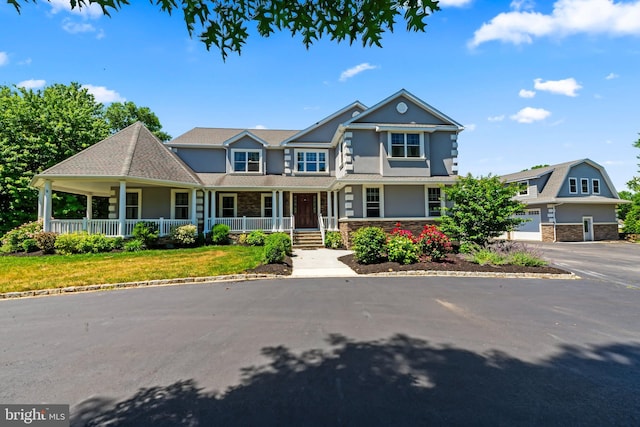 view of front of property with a front lawn, covered porch, and a garage