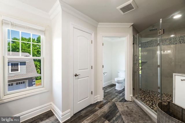 bathroom featuring crown molding, wood-type flooring, a shower with shower door, and toilet