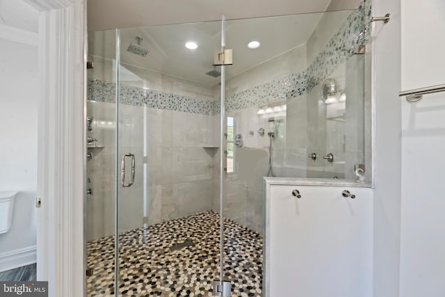 bathroom featuring toilet and a shower with shower door