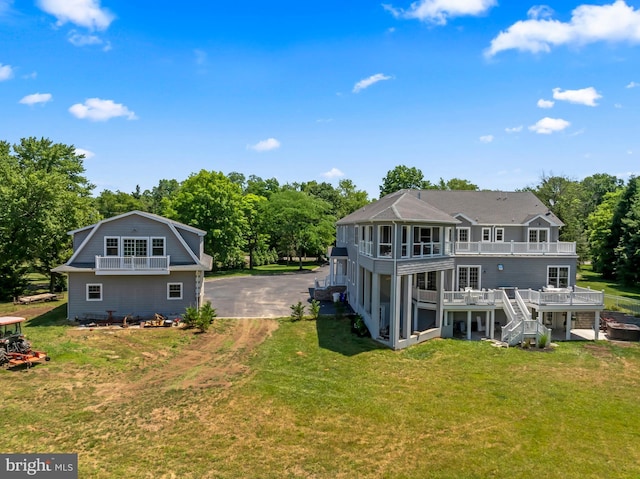 back of property with a wooden deck, a sunroom, and a yard