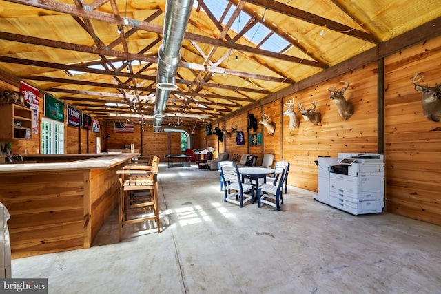 misc room featuring vaulted ceiling and wooden walls